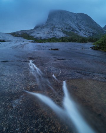 Foto de Pequeño arroyo fluye a través de losas rocosas debajo del pico de montaña Kulhornet, Nordland, Noruega - Imagen libre de derechos