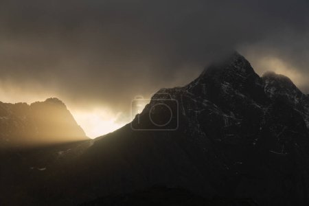 Foto de Rayo de luz del sol brilla detrás de Himmeltandan picos de montaña, Vestvgy, Islas Lofoten, Noruega - Imagen libre de derechos
