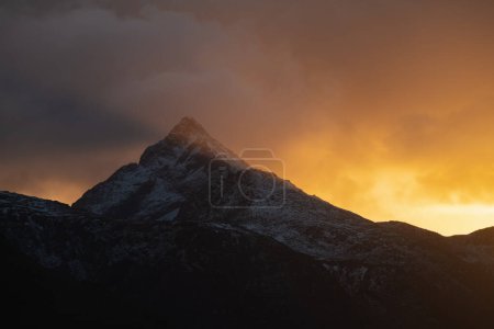 Téléchargez les photos : Le soleil d'hiver brille derrière le sommet de la montagne Skottind, Vestvgy, Îles Lofoten, Norvège - en image libre de droit