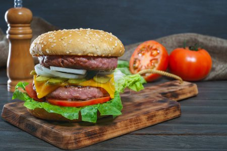 Foto de Primer plano de una deliciosa hamburguesa entera en una tabla de madera y salsas - Imagen libre de derechos