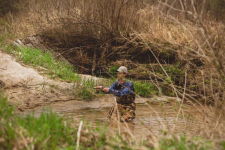 Téléchargez les photos : Jeune homme coulée canne à pêche dans l'eau du ruisseau - en image libre de droit