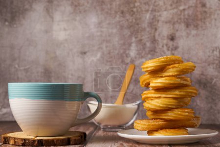 Photo for Hot chocolate with churros in a white and blue cup ,typical spanish breakfast on a wooden table - Royalty Free Image