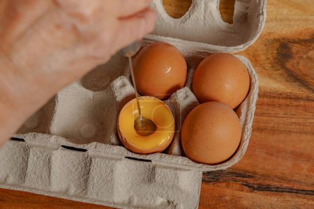 Foto de Mujer batiendo un huevo en su propia cáscara con una pequeña licuadora, varios huevos en una taza de huevo - Imagen libre de derechos