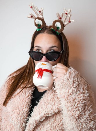 Téléchargez les photos : Fille profiter de Noël avec un latte et un bandeau de renne - en image libre de droit