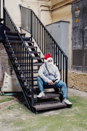 Photo for Homeless Santa drinking wine and rummaging through garbage bins - Royalty Free Image
