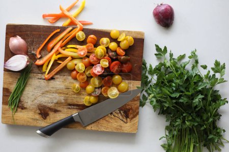 Foto de Tomates, cebolla, pimientos y perejil en la tabla de cortar - Imagen libre de derechos