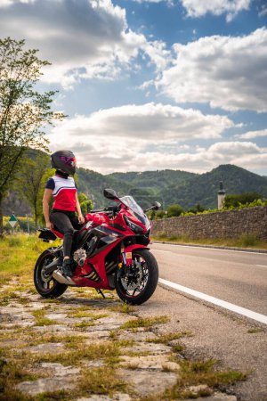 Téléchargez les photos : Journée nuageuse avec une incroyable jeune fille motard sur sa moto - en image libre de droit