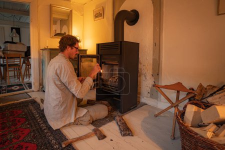 Man Starting Fireplace In Old Cottage House Wood Stove