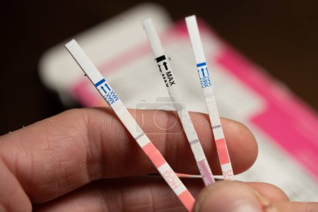 Téléchargez les photos : Man Hold 3 Negative HCG Pregnancy Test With his Fingers - Close Up - en image libre de droit