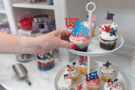 Téléchargez les photos : Femme main prend le 4 Juillet cupcakes thème hors plaque d'affichage - en image libre de droit