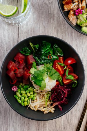 Foto de Asian poke bowl with rice, vegetables and fresh tuna - Imagen libre de derechos