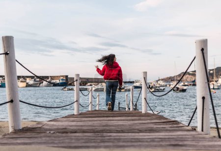 Téléchargez les photos : Woman walking on the wooden pier in front of the sea - en image libre de droit