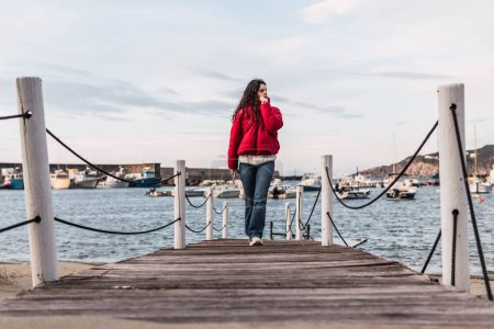Téléchargez les photos : Woman walking on the wooden pier in front of the sea - en image libre de droit