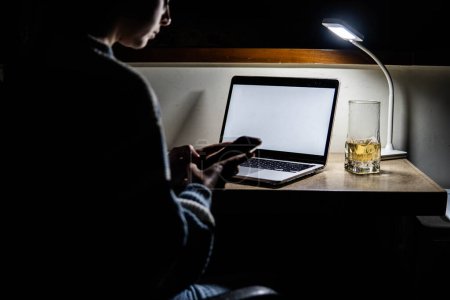 Téléchargez les photos : Girl working on computer and mobile phone at home at night - en image libre de droit