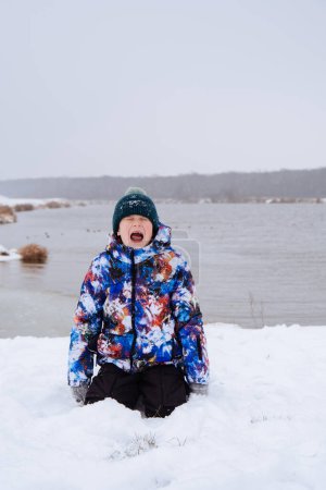 Foto de Niño feliz divirtiéndose jugando con la nieve en el día de invierno - Imagen libre de derechos