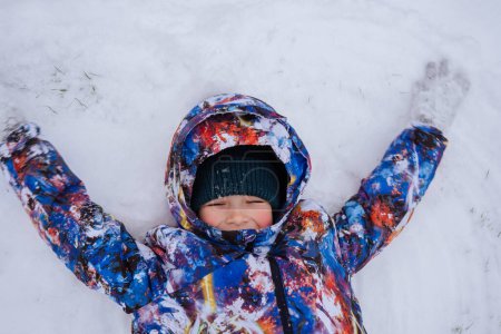Foto de Niño feliz divirtiéndose jugando con la nieve en el día de invierno - Imagen libre de derechos