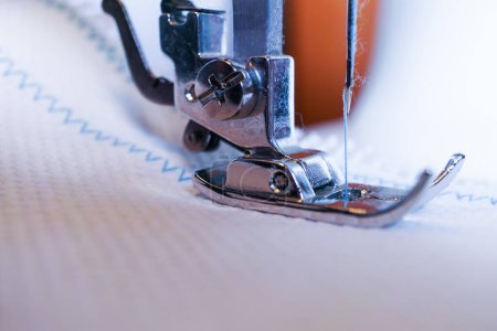 Foto de Close-up of sewing machine needle with blue thread sewing on a white fabric - Imagen libre de derechos