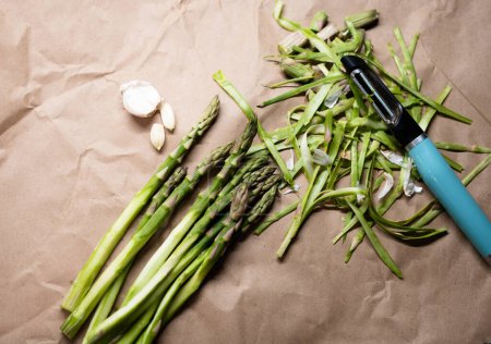 Téléchargez les photos : Bunch of green peeled asparagus with garlic  on the table - en image libre de droit