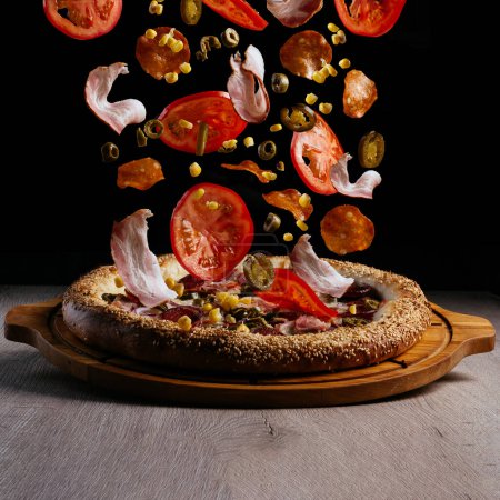 Foto de Levitating pizza ingredients. pizza on a wooden board - Imagen libre de derechos
