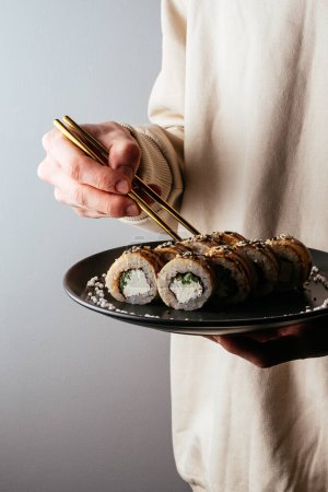 Foto de A man holds a plate of sushi. - Imagen libre de derechos