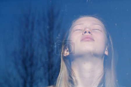Foto de Una adolescente se refleja en la ventana en un clima soleado. Psicología - Imagen libre de derechos