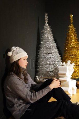 Foto de Un adolescente con un sombrero de doncella de nieve se sienta sobre un fondo de abetos - Imagen libre de derechos