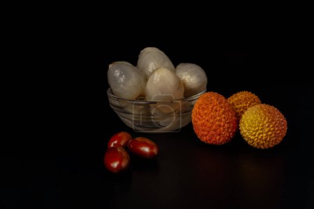 Téléchargez les photos : Whole fresh lychees, peeled and with their bones on a black background - en image libre de droit