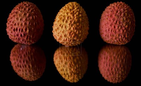 Téléchargez les photos : Close-up of three fresh lychees reflected in a mirror on a black background - en image libre de droit