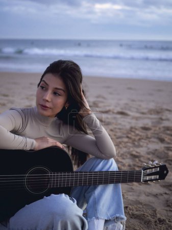 Foto de Young Woman with guitar sitting Close Ocean - Imagen libre de derechos