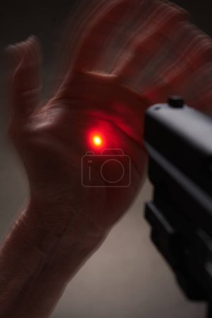 Photo for Expressive hands in front of a pistol with a laser gunsight - Royalty Free Image