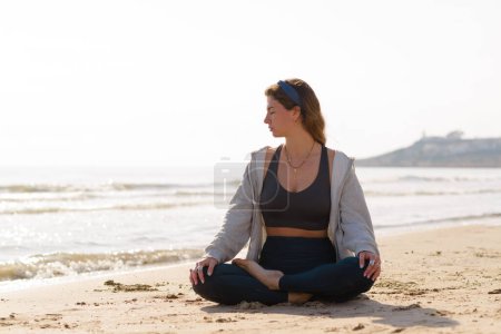 Téléchargez les photos : Young woman does yoga on the beach - en image libre de droit