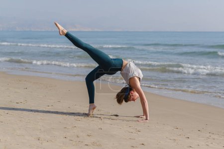 Foto de Young woman does yoga on the beach - Imagen libre de derechos
