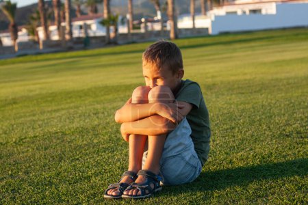 Photo for The boy is sitting and thinking on the golf course. - Royalty Free Image