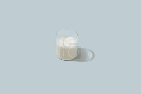 Photo pour Milk in a clear glass glass on a light blue background - image libre de droit