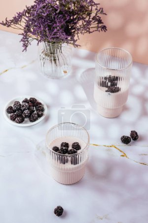 Photo for Yogurt with berries in a glass on a light pink background - Royalty Free Image