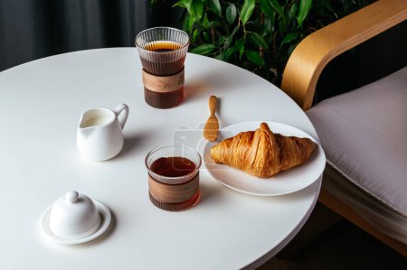 Photo for Coffee and croissant on a plate on a white table in the living room - Royalty Free Image