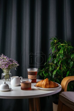 Foto de Coffee and croissant on a plate on a white table in the living room - Imagen libre de derechos
