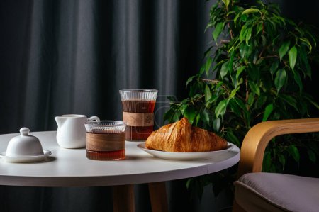 Téléchargez les photos : Coffee and croissant on a plate on a white table in the living room - en image libre de droit