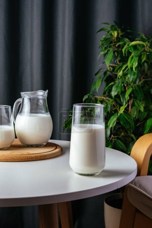 Photo for Milk in a glass on a white table - Royalty Free Image