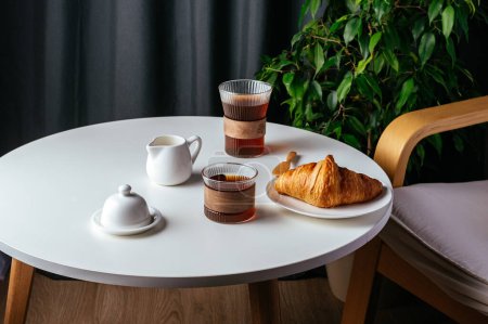 Photo for Coffee and croissant on a plate on a white table in the living room - Royalty Free Image