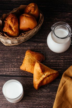 Photo for Pasties stuffed and glass of milk on a dark background. - Royalty Free Image