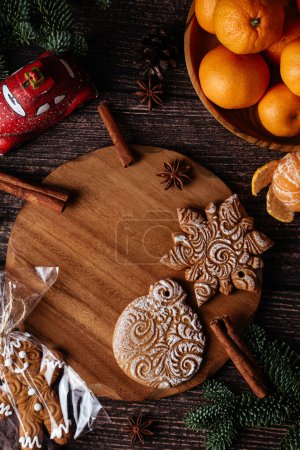 Foto de Christmas New Year composition with tangerines, anise, cinnamon sticks and green fir tree branches on a dark background. Holiday decoration. - Imagen libre de derechos