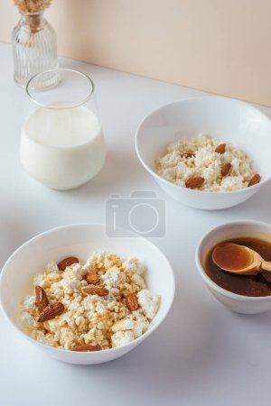 Téléchargez les photos : Cottage cheese in a white bowl with nuts and honey on a light background - en image libre de droit