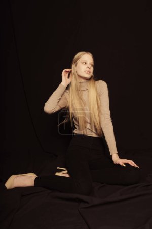 Foto de Portrait of a beautiful woman with long blonde hair blowing in a wind, wearing long black gothic costume. isolated against a black background. - Imagen libre de derechos