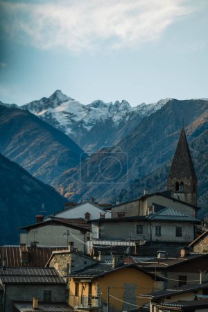 Téléchargez les photos : Exterior of aged residential houses located near snowy mountains against cloudy sky in sunny weather - en image libre de droit