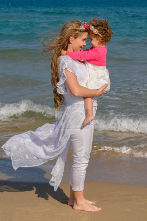 Téléchargez les photos : Mother and daughter standing on the beach in summer - en image libre de droit