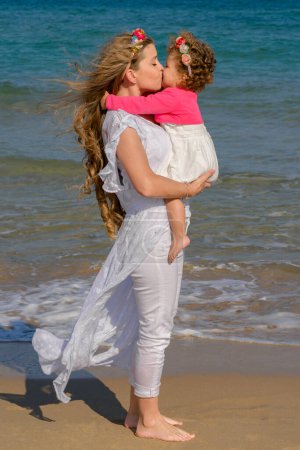 Téléchargez les photos : Mother and daughter kissing on the beach in summer - en image libre de droit