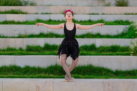 Photo for Cheerful young girl, wearing black ballet outfit, demonstrating her outdoor art. - Royalty Free Image