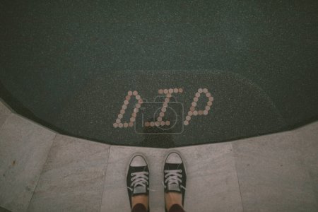 Foto de Converse shoes standing by the pool step with tiles that spell d - Imagen libre de derechos
