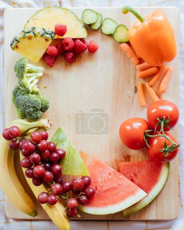 Foto de Un círculo de productos orgánicos en la tabla de cortar madera con frutas y - Imagen libre de derechos